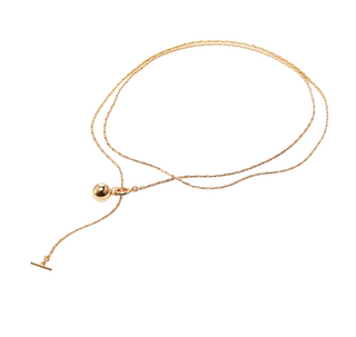 Gold necklace with a small round pendant on a light beige background